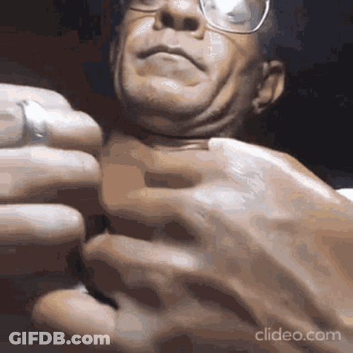 A Close Up Of A Man 'S Face With Glasses Being Squeezed . GIF