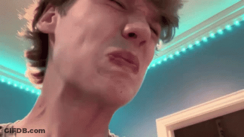 A Close Up Of A Man 'S Face With His Eyes Closed And A Blue Wall In The Background . GIF