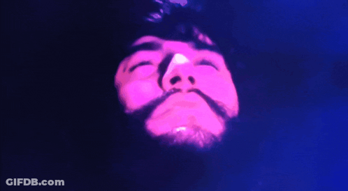 A Close Up Of A Man 'S Face With His Eyes Closed And A Pink Light Behind Him GIF