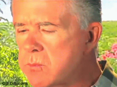 A Close Up Of A Man 'S Face With His Eyes Closed In A Field GIF