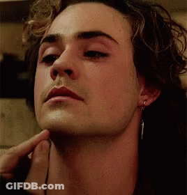 A Close Up Of A Man 'S Face With His Hand On His Chin And Earrings . GIF