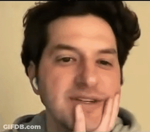 A Close Up Of A Man 'S Face With His Hand On His Chin And Headphones On . GIF