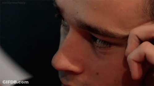 A Close Up Of A Man 'S Face With His Hand On His Face . GIF