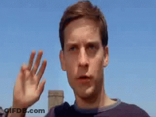 A Close Up Of A Man 'S Face With His Hand Up In The Air . GIF