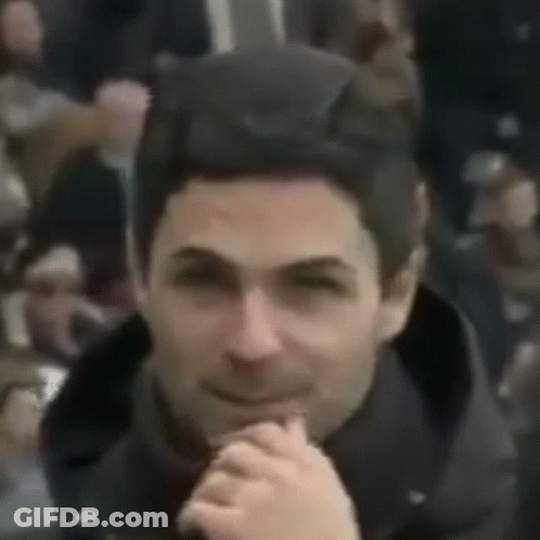 A Close Up Of A Man 'S Face With His Hands Folded And A Crowd Behind Him . GIF