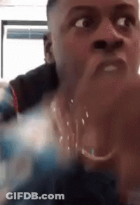 A Close Up Of A Man 'S Face With His Hands Folded In Front Of His Mouth . GIF