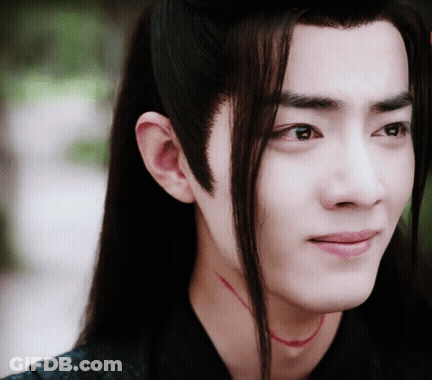A Close Up Of A Man 'S Face With Long Hair And A Red Necklace Around His Neck GIF