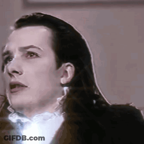 A Close Up Of A Man 'S Face With Long Hair And A White Shirt GIF