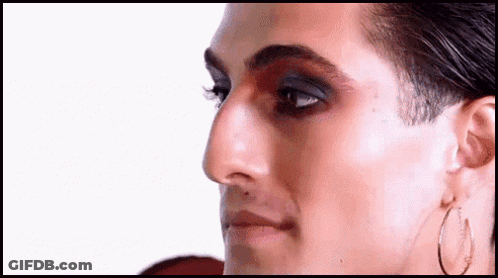 A Close Up Of A Man 'S Face With Makeup And Hoop Earrings On . GIF