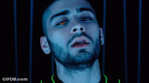 A Close Up Of A Man 'S Face With Red Eyes And A Beard In A Dark Room . GIF
