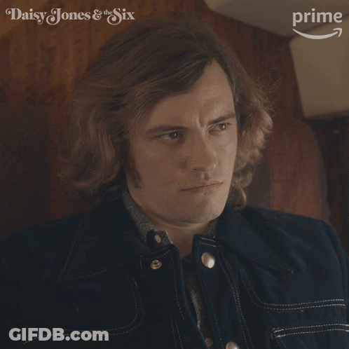 A Close Up Of A Man 'S Face With The Words Daisy Jones & The Six In The Background GIF