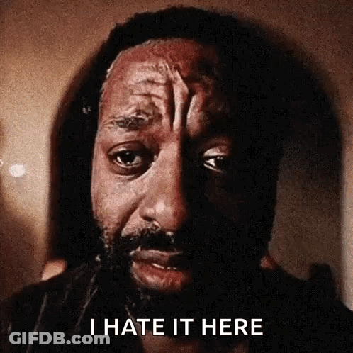 A Close Up Of A Man 'S Face With The Words `` I Hate It Here '' Written On The Bottom . GIF