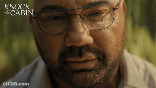 A Close Up Of A Man 'S Face With The Words " Knock At The Cabin " Behind Him GIF