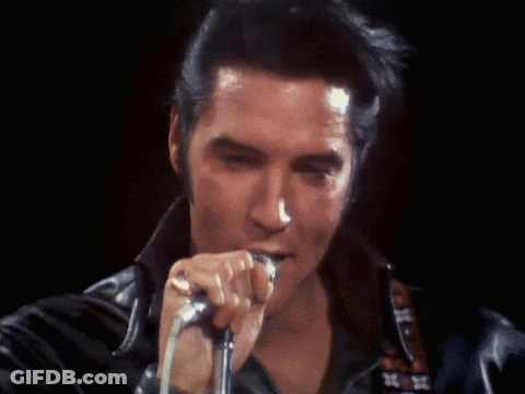 A Close Up Of A Man Singing Into A Microphone In A Dark Room GIF