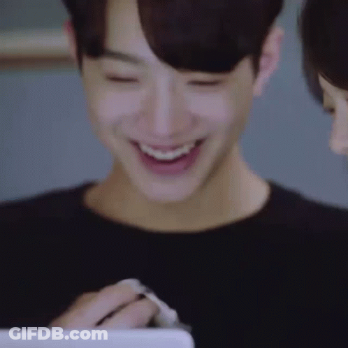 A Close Up Of A Man Smiling While Looking At A Tablet . GIF