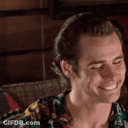 A Close Up Of A Man Smiling With His Eyes Closed And Wearing A Floral Shirt . GIF