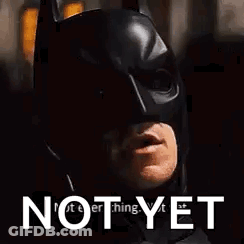 A Close Up Of A Man Wearing A Batman Mask With The Words `` Not Yet '' Above Him . GIF