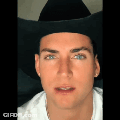 A Close Up Of A Man Wearing A Black Cowboy Hat And A White Shirt . GIF