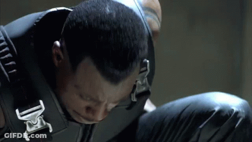 A Close Up Of A Man Wearing A Black Vest With A Buckle That Says Dc GIF
