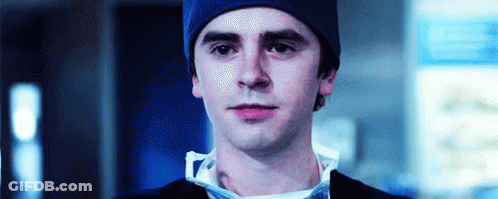 A Close Up Of A Man Wearing A Blue Beanie And A Surgical Mask . GIF