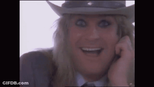 A Close Up Of A Man Wearing A Cowboy Hat And Smiling While Talking On A Cell Phone . GIF