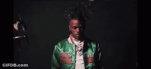 A Close Up Of A Man Wearing A Green Jacket And A Necklace . GIF