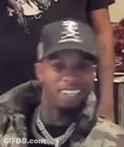 A Close Up Of A Man Wearing A Hat And A Chain . GIF