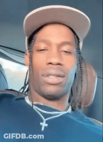 A Close Up Of A Man Wearing A Hat And A Necklace With A Cross On It . GIF