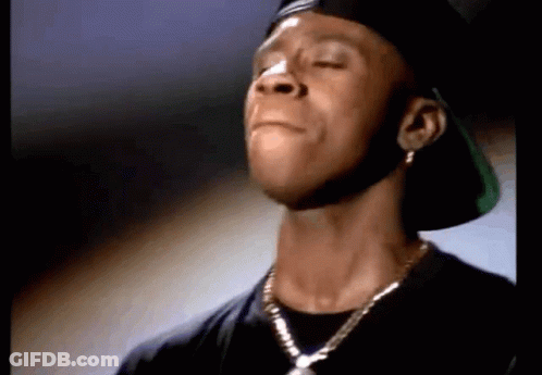 A Close Up Of A Man Wearing A Hat And A Necklace With His Eyes Closed GIF