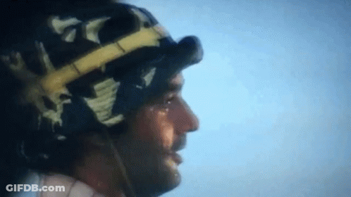 A Close Up Of A Man Wearing A Helmet And Goggles Against A Blue Sky GIF