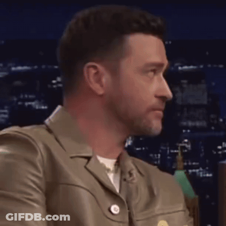 A Close Up Of A Man Wearing A Leather Jacket Looking To The Side . GIF
