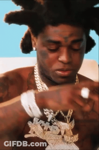 A Close Up Of A Man Wearing A Necklace With The Word Vulture On It GIF
