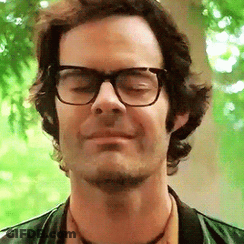 A Close Up Of A Man Wearing Glasses And A Green Jacket GIF