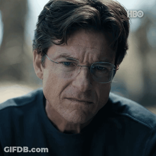A Close Up Of A Man Wearing Glasses And A Hbo Logo In The Background GIF