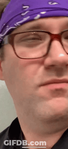 A Close Up Of A Man Wearing Glasses And A Purple Headband GIF
