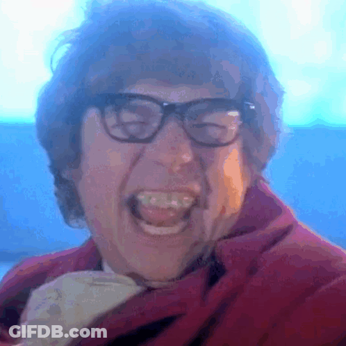 A Close Up Of A Man Wearing Glasses And A Red Jacket GIF