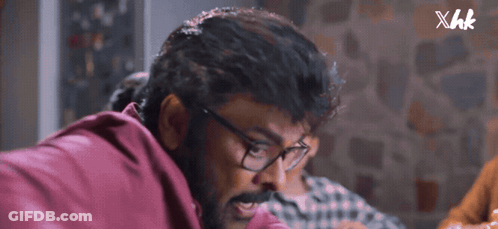 A Close Up Of A Man Wearing Glasses And A Red Shirt With Xhk Written On The Bottom GIF