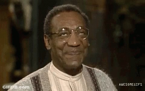A Close Up Of A Man Wearing Glasses And A Sweater And Smiling . GIF