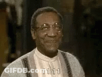 A Close Up Of A Man Wearing Glasses And A Sweater Smiling . GIF