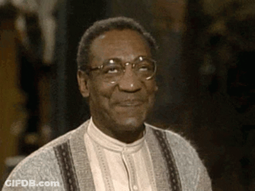 A Close Up Of A Man Wearing Glasses And A Sweater Smiling GIF