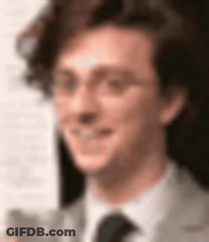A Close Up Of A Man Wearing Glasses And A Tie GIF