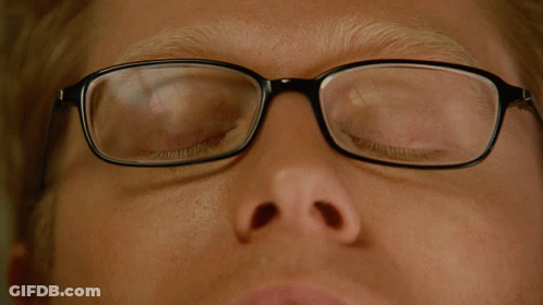 A Close Up Of A Man Wearing Glasses With His Eyes Looking Up GIF
