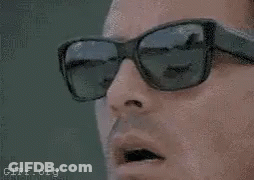 A Close Up Of A Man Wearing Sunglasses And A Cell Phone . GIF