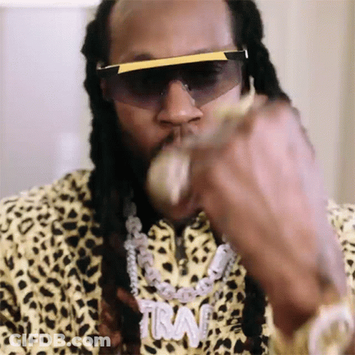 A Close Up Of A Man Wearing Sunglasses And A Necklace With The Word Trav On It GIF