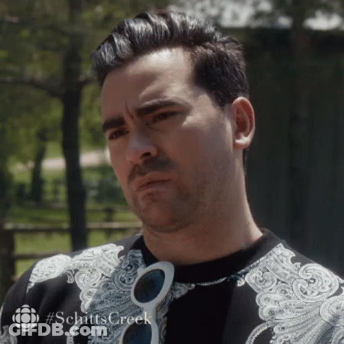 A Close Up Of A Man Wearing Sunglasses And A Shirt With #Schitts Creek On It GIF