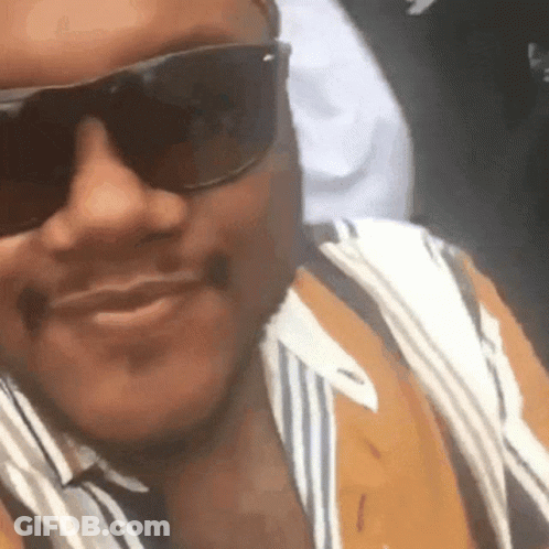 A Close Up Of A Man Wearing Sunglasses And A Striped Shirt GIF