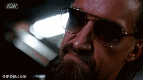 A Close Up Of A Man Wearing Sunglasses With The Aew Logo On The Bottom GIF