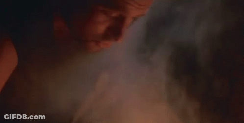 A Close Up Of A Man With A Beard Smoking A Cigarette In A Dark Room . GIF