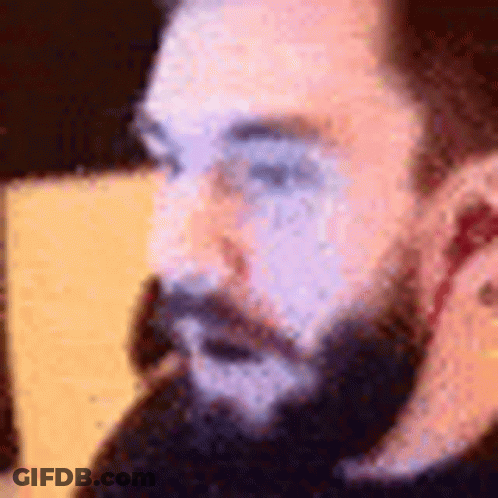 A Close Up Of A Man With A Beard Talking On A Phone . GIF