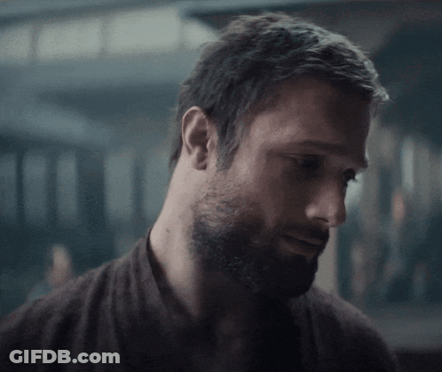 A Close Up Of A Man With A Beard Wearing A Brown Shirt GIF